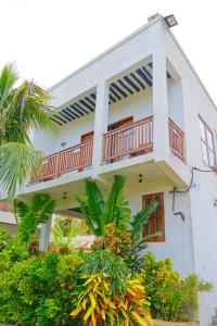a white house with a balcony and plants at Bustan in Matemwe