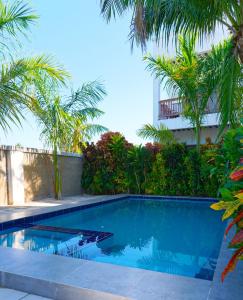 a swimming pool with palm trees and a building at Bustan in Matemwe