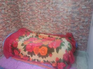 a bed with a floral comforter in front of a brick wall at بيت مع وجبة إفطار لمشجعي كأس الأمم الأفريقية in Fez