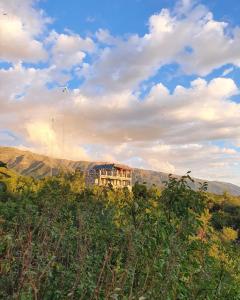 een huis bovenop een heuvel met bergen op de achtergrond bij Hostería Vegetariana in Country Club Chumamaya +4 foto's