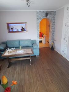 ein Wohnzimmer mit einem blauen Sofa und einem Tisch in der Unterkunft Ferienwohnung ILSENHOF in Königsbrück