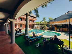 een groep mensen die rond een zwembad in een resort zitten bij Viajero Puerto Escondido Hostel in Puerto Escondido