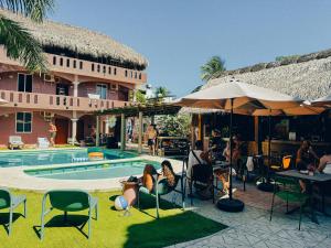 a group of people sitting in chairs by a swimming pool at Viajero Puerto Escondido Hostel in Puerto Escondido