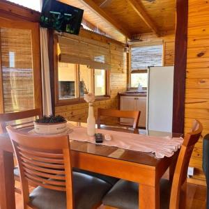 une salle à manger avec une table et une télévision dans l'établissement El Refugio del Lago en Potrero de Garay, à La Estancia