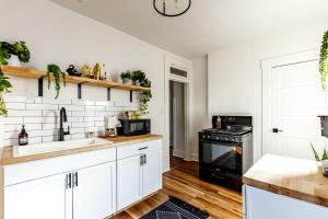 een keuken met witte kasten en een zwarte kachel bij Jungle House Columbus Downtown Free Parking Sleeps 8 - Near Convention Center & Nationwide Arena - 2BR Luxury Home - Pet Friendly Over 5,800 Five Star Stays in Columbus