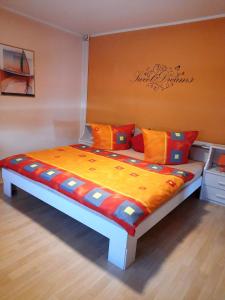 Bett in einem Zimmer mit orangefarbenen und blauen Kissen in der Unterkunft Ferienwohnung ILSENHOF in Königsbrück