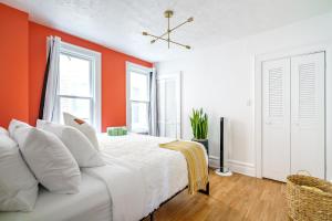 een slaapkamer met oranje muren en een bed met witte kussens bij Jungle House Luxury Homes - Columbus Downtown Short North - Walk to Convention Center & Nationwide Arena - Sleeps up to 8 - Free Parking - Over 5,800 Five Stars in Columbus