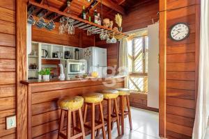 eine Küche mit einer Bar mit Hockern und einer Uhr in der Unterkunft Casa Aconchegante – A 200m da praia da Pinheira in Pinheira + 13 Fotos