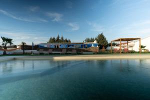 une piscine d'eau en face d'un bâtiment dans l'établissement Herdade da Yucca - Retreat & Spa, à Terena