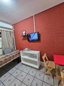 a room with a red wall with a tv on the wall at Sonhos de Penha - Chalés e Aptos in Penha