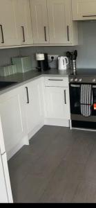a kitchen with white cabinets and a black oven at Private modern guest house in Yetminster