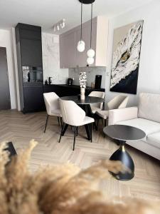een woonkamer met een bank, een tafel en stoelen bij Nadmorski Apartament B5 in Gąski