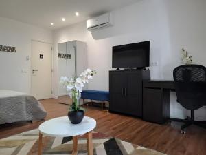 een woonkamer met een televisie en een tafel met een vaas met bloemen bij Zizas House Studio in Praia da Rocha