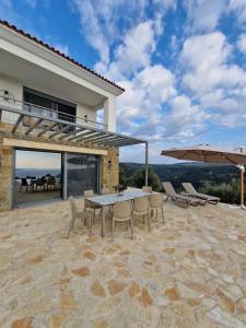 a patio with a table and chairs and an umbrella at Seeview Villa and Mountain view in Grizókambos