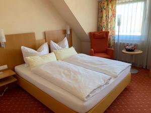 una camera da letto con un grande letto bianco e una sedia di Hotel Möhringer Hof a Stoccarda