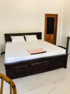 a bed in a room with a wooden bed frame at Nimal's villa in Midigama East