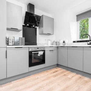 a white kitchen with white cabinets and an oven at Modern Two Bed Apartment - Netflix - Balcony - Parking - 5MC in Birmingham