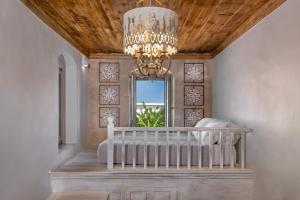 a bedroom with a crib and a chandelier at Melitia Traditional House in Koskinou