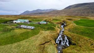 Een luchtfoto van een boerderij in een veld met een waterval. bij Stóra-Ásgeirsá Horse Farm Stay in Víðigerði