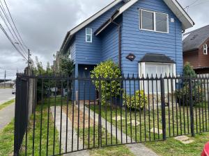 a blue house with a fence in front of it at Casa piedra in Puerto Montt