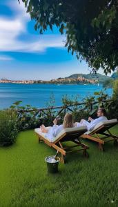 un gruppo di persone sdraiate su sedie a sdraio sull'erba di Alma Capodimonte Lake chalet a Capodimonte
