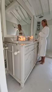 una donna in piedi di fronte a uno specchio del bagno di Alma Capodimonte Lake chalet a Capodimonte