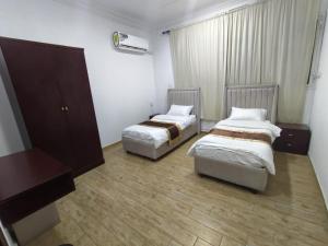 a hotel room with two beds and a dresser at العروسة للشقق المخدومة in Tabuk