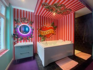 La salle de bains est pourvue d'un mur rayé rouge et blanc. dans l'établissement Capsule Tattoo Love, à Douai