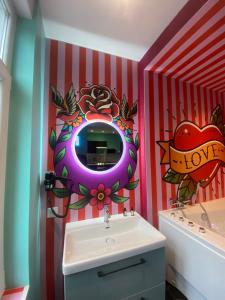 une salle de bain avec un lavabo et un miroir au mur dans l'établissement Capsule Tattoo Love, à Douai 16 autres photos