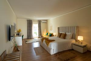 une chambre avec un grand lit blanc et une télévision dans l'établissement Herdade da Yucca - Retreat & Spa, à Terena