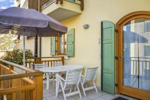 een tafel en stoelen op een balkon met een parasol bij Windshouse Apartments in Nago-Torbole