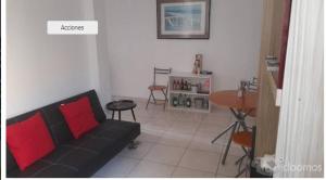 een woonkamer met een zwarte bank en een tafel bij Aloha in San Bartolo