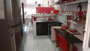 a kitchen with a black counter and red cabinets at Seu Refúgio a 100m da Praia do Sobral - Maceió in Maceió