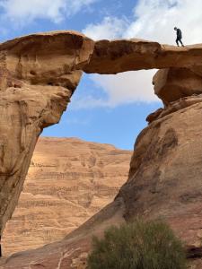 a man standing on a rock formation in the desert at Eileen wadi rum camp in Wadi Rum