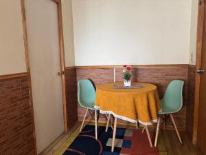 a table with three chairs and a vase of flowers on it at Family Summer House in Valparaíso