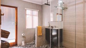 a bathroom with a sink and a glass shower at Breathe Accommodation in Oudtshoorn +81 photos