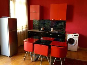 a kitchen with red cabinets and a table with red chairs at Guest House Lali Kostava 14 in Zugdidi