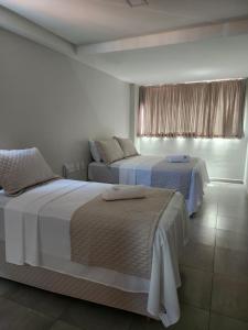 a bedroom with two beds and a window at Murano Suits Hotel in João Pessoa