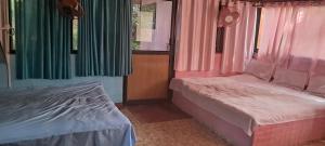 a bedroom with two beds and colorful curtains at Shree MAHAGANAPATI ROOMS 6 bed room only for gents in Gokarna