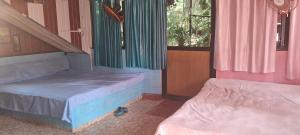two beds in a room with pink and green curtains at Shree MAHAGANAPATI ROOMS 6 bed room only for gents in Gokarna