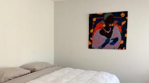 ein Schlafzimmer mit einem Bett und einem Gemälde an der Wand in der Unterkunft Temporario Sur, hasta 4 personas con 3 camas, General Roca in General Roca