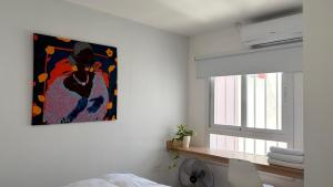 ein Schlafzimmer mit einem Gemälde an der Wand neben einem Fenster in der Unterkunft Temporario Sur, hasta 4 personas con 3 camas, General Roca in General Roca