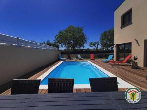a swimming pool with chairs and a house at La villa manon in Florensac