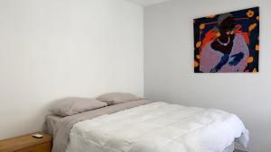 ein Schlafzimmer mit einem Bett und einem Gemälde an der Wand in der Unterkunft Temporario Sur, hasta 4 personas con 3 camas, General Roca in General Roca