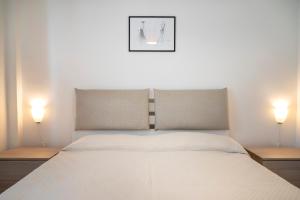 a bedroom with a white bed with two lamps at M377 - Marcelli, bilocale con corte esterna e posto auto in Marcelli
