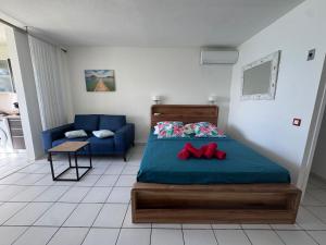 een slaapkamer met een bed en een blauwe bank bij Yucca Sea View in Le Gosier