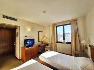 a hotel room with two beds and a television at Hotel Excelsior Magenta in Magenta
