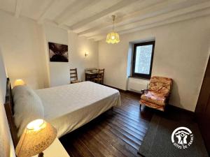 a bedroom with a bed and a chair and a window at Le gite fleuri in Limousis