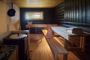 a wooden room with a bench and a table at Capture Nordic Wilderness Camp in Ilomantsi