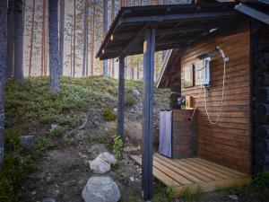 een houten hut met een douche op een terras bij Capture Nordic Wilderness Camp in Ilomantsi